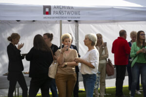 Kilkanaście osób stoi i rozmawia pod białym namiotem z napisem Archiwa Państwowe Archiwum Państwowe w Koszalinie.