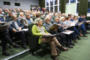 Publiczność w sali kinowej siedzi i przegląda publikację.
