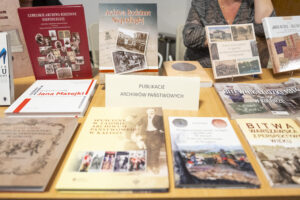 Kilka książek leży na stole. Wśród nich kartonik z napisem Publikacje Archiwów Państwowych.