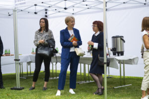 Trzy kobiety stoją pod białym namiotem. W tle stół z przekąskami.