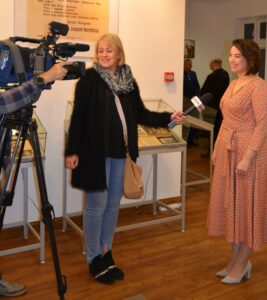 Dwie kobiety stoją na przeciwko siebie. Jedna z nich trzyma mikrofon. Po lewej stronie kamera.