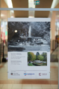 Stojak wystawowy z wyeksponowanym zdjęciem fontanny w parku w przeszłości i dziś.